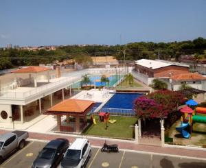 a building with a pool and cars parked in a parking lot at Apto Completo! 2 Quartos! in São Luís
