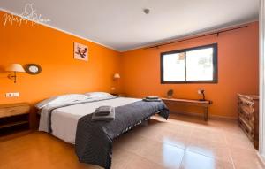 Schlafzimmer mit orangefarbenen Wänden, einem Bett und einem Fenster in der Unterkunft B-Rent Mariposa Private Garden in Corralejo