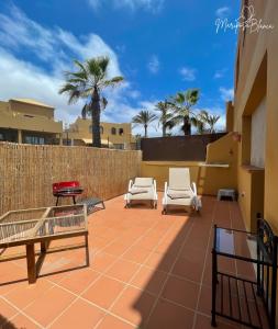 eine Terrasse mit 2 Stühlen, einem Tisch und Palmen in der Unterkunft B-Rent Mariposa Private Garden in Corralejo