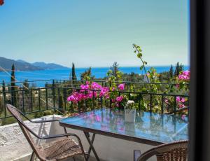 una mesa y sillas en un balcón con flores rosas en Giovanni Group Apartments, en Sivota