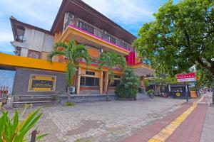 een gebouw met palmbomen voor een straat bij OYO 3244 Grand Chandra Hotel in Denpasar