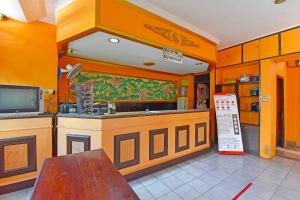 uma cozinha com paredes cor de laranja, um lavatório e um balcão em OYO 3244 Grand Chandra Hotel em Denpasar
