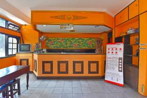 a kitchen with orange walls and a kitchen with a counter at OYO 3244 Grand Chandra Hotel in Denpasar