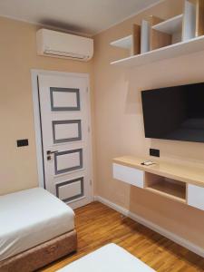 um quarto com uma cama, uma televisão e uma porta em Olives Residence em Dhërmi