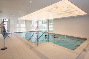 due persone che nuotano in una piscina in un edificio di Résidence services seniors DOMITYS LES EAUX VIVES a Digne-Les-Bains