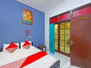 1 dormitorio con 1 cama con paredes rojas y azules en OYO 3244 Grand Chandra Hotel, en Denpasar