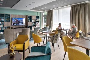 a library with people sitting at tables and chairs at Résidence services seniors DOMITYS LES EAUX VIVES in Digne-les-Bains