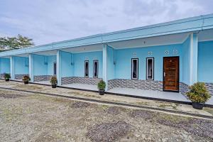 ein blaues Gebäude mit Pflanzen davor in der Unterkunft OYO 91334 Permata Papua Guest House in Pameungpeuk