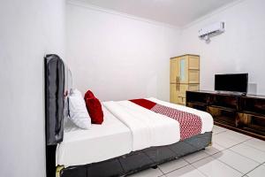 ein Schlafzimmer mit einem großen Bett und einem TV in der Unterkunft OYO 91334 Permata Papua Guest House in Pameungpeuk