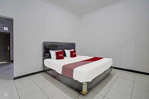ein Schlafzimmer mit einem Bett mit roten Kissen darauf in der Unterkunft OYO 91334 Permata Papua Guest House in Pameungpeuk
