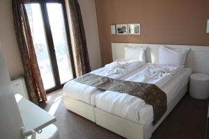 a bedroom with a white bed with a large window at Milano Hotel in Burgas +37 photos