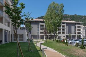 een appartementencomplex met auto's geparkeerd op een parkeerplaats bij Résidence services seniors DOMITYS LES EAUX VIVES in Digne-les-Bains