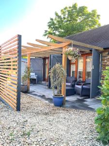 a patio with a wooden pergola and plants at Lavender Cottage - Hillside Holiday Cottages, Cotswolds in Warmington