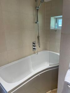 a white bath tub with a shower in a bathroom at Lavender Cottage - Hillside Holiday Cottages, Cotswolds in Warmington