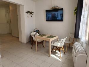 a room with a table and chairs and a tv on the wall at Suquet 22 – 2 Pièces, Cannes Cœur Historique, Calme, Plage à 300m, Parking in Cannes