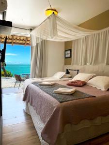 a bedroom with a bed with a view of the ocean at Pousada Ponta da Vigia in Penha