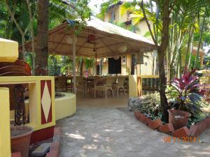 un patio con sombrilla, mesas y sillas en Palolem Guest House, en Palolem