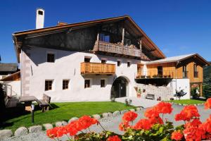 a large white building with a balcony and red flowers at Huberhof in Natz-Schabs