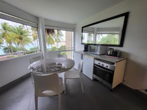 eine Küche mit einem Tisch und 2 Fenstern sowie einem Tisch und Stühlen in der Unterkunft Résidence Appartement La Vieille Tour in Le Gosier