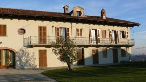 une grande maison blanche avec un arbre en face dans l'établissement Villa Crissante, à La Morra