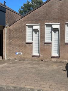 a brick building with white shuttered windows on it at Gezellige knusse studio met bubbelbad in Huizen