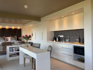 a kitchen with white cabinets and a white table at Cape Vermeer in Somerset West