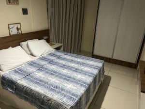 a bedroom with a bed with a blue and white blanket at Flat beira mar Tambaú in João Pessoa