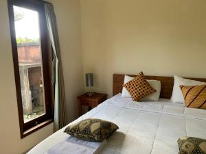 a bedroom with a large white bed with a window at Wonder-Land Villa in Ubud