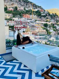 Eine Frau, die in einer Badewanne auf einem Gebäude sitzt. in der Unterkunft Villa Diamond Luxury Suite in Positano