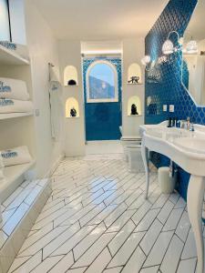a blue and white bathroom with a sink and a tub at Villa Diamond Luxury Suite in Positano