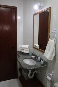 ein Bad mit einem Waschbecken und einem Spiegel in der Unterkunft CASA GORETE PRAIA DAS DUNAS RESIDENCE CLUB in Cabo Frio