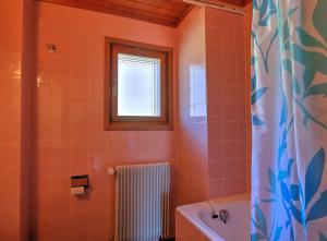 baño con azulejos de color naranja, ventana y bañera en Appartement Les Cascades, en Château-d'Oex