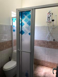 La salle de bains est pourvue de toilettes et d'une porte de douche en verre. dans l'établissement One-Room Homestay 81B Muar, à Muar