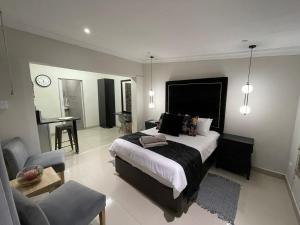 a bedroom with a bed and a chair and a table at The Guesthouse Klerksdorp in Klerksdorp