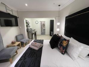a bedroom with a large white bed and a chair at The Guesthouse Klerksdorp in Klerksdorp