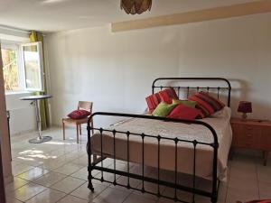 a bedroom with a bed with red and green pillows at Appartement dans maison individuelle LE CAYLUS BAS in Saint-Affrique