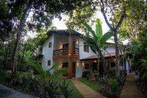 a house with a balcony in the middle of trees at Casa Gungalilin Trancoso in Trancoso