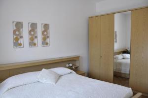 Schlafzimmer mit einem weißen Bett und einem Spiegel in der Unterkunft Appartamento Alba in Riva del Garda
