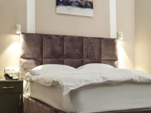 a bed with a padded headboard in a bedroom at Ritz Hotel in Atyraū