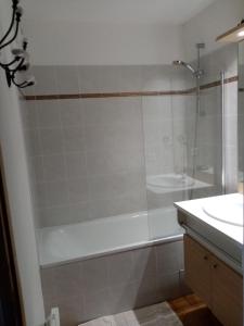 y baño con ducha, bañera y lavamanos. en Appartement calme au pied des pistes en Valmeinier