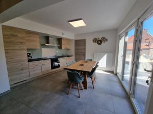 cocina con mesa de madera y sillas en Les Cayaux en Brugelette