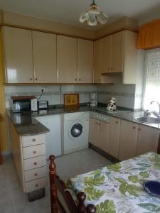 a kitchen with a sink and a washing machine at Apartamento Playa de Coto in Barreiros