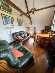 a living room with a leather couch and a table at Cwmgwn Farm in Llandovery