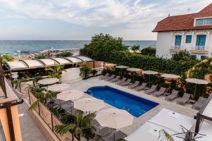 un patio al aire libre con mesas, sombrillas y el océano en AB BOUTIQUE HOTEL - Adults only en San Vicenç de Montalt