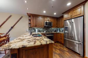 a kitchen with wooden cabinets and a stainless steel refrigerator at Powderhorn Lodge 408: Rustic Mountain Suite in Solitude