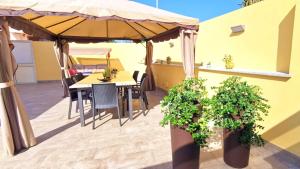 een patio met een tafel en stoelen en een parasol bij La Villa Trinacria in Giardini Naxos