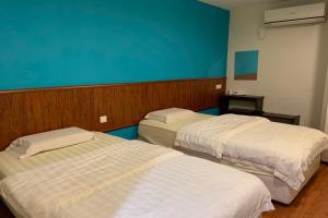 a room with two beds and a blue wall at Super OYO 90579 U Inn in Miri