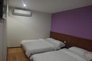 2 Betten in einem Zimmer mit einer lila und weißen Wand in der Unterkunft Super OYO 90579 U Inn in Miri