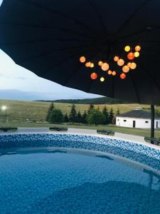 a swimming pool with an umbrella next to at Aranyló Vendégház in Alsótelekes