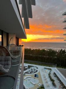 a view of the sunset from the balcony of a resort at Wave Resort & Spa Magic Apartaments with sea view in Międzyzdroje